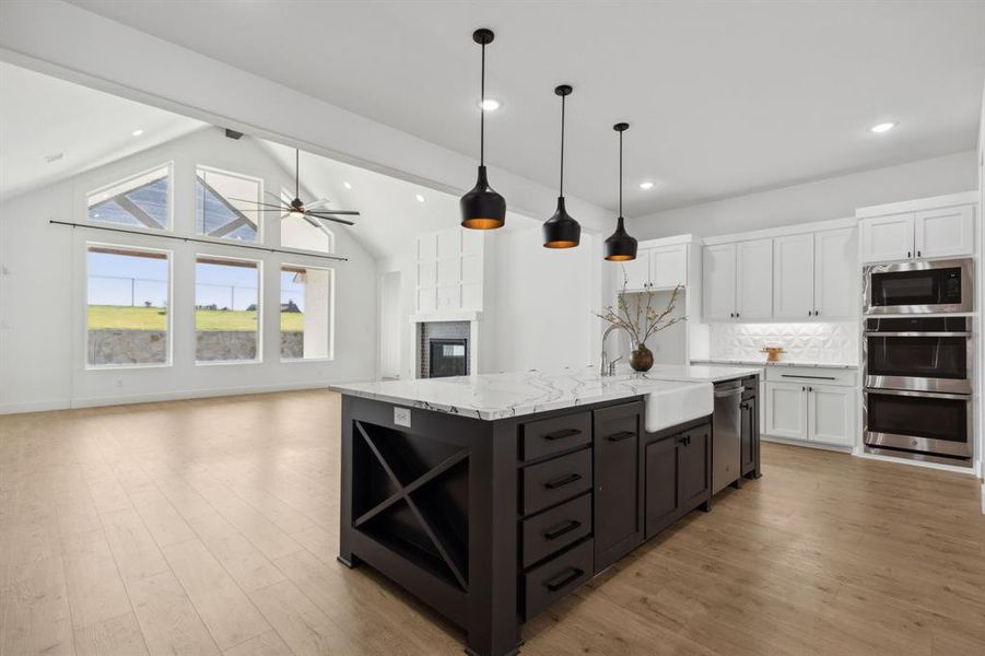 Kitchen with lofted ceiling with beams, sink, an island with sink, and white cabinets