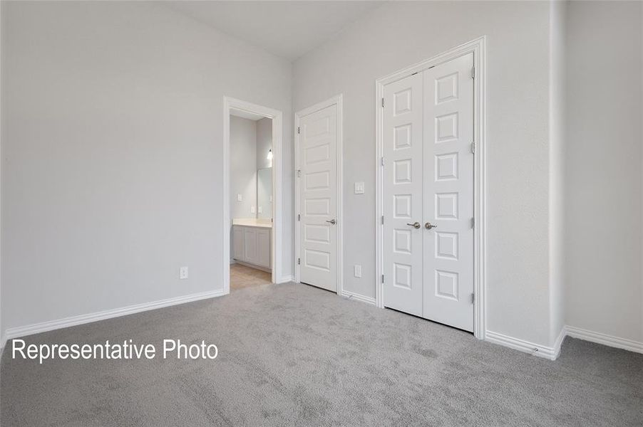 Unfurnished bedroom with connected bathroom and light colored carpet