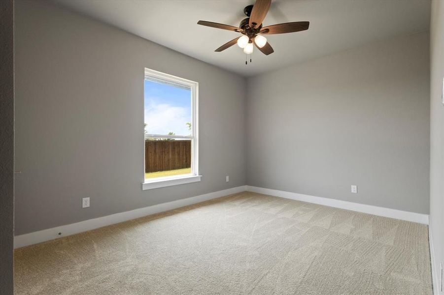 Carpeted empty room featuring ceiling fan