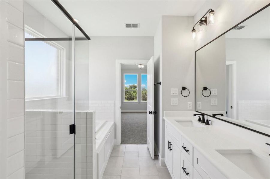 Bathroom with tile patterned floors, dual bowl vanity, and a tub to relax in