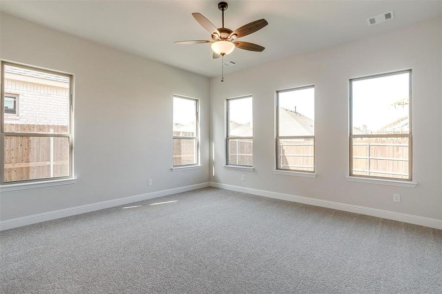 Carpeted spare room featuring ceiling fan and plenty of natural light