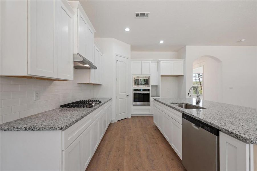 Kitchen featuring white cabinetry, light hardwood / wood-style flooring, sink, range hood, and stainless steel appliances