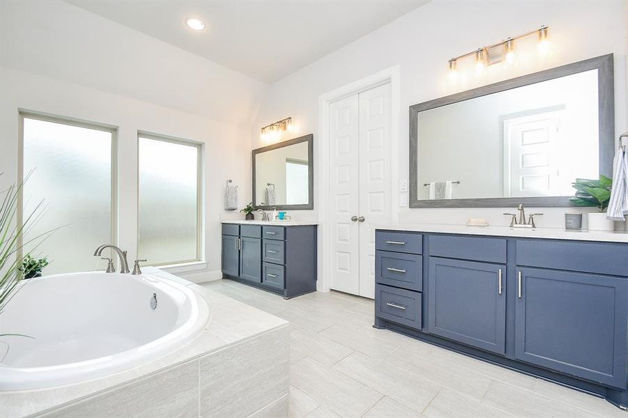 The primary modern, bright bathroom features a large built-in bathtub with tile surround, a separate walk-in shower with glass doors, 2 walk-in closets, 2 separate vanities and separate toilet room