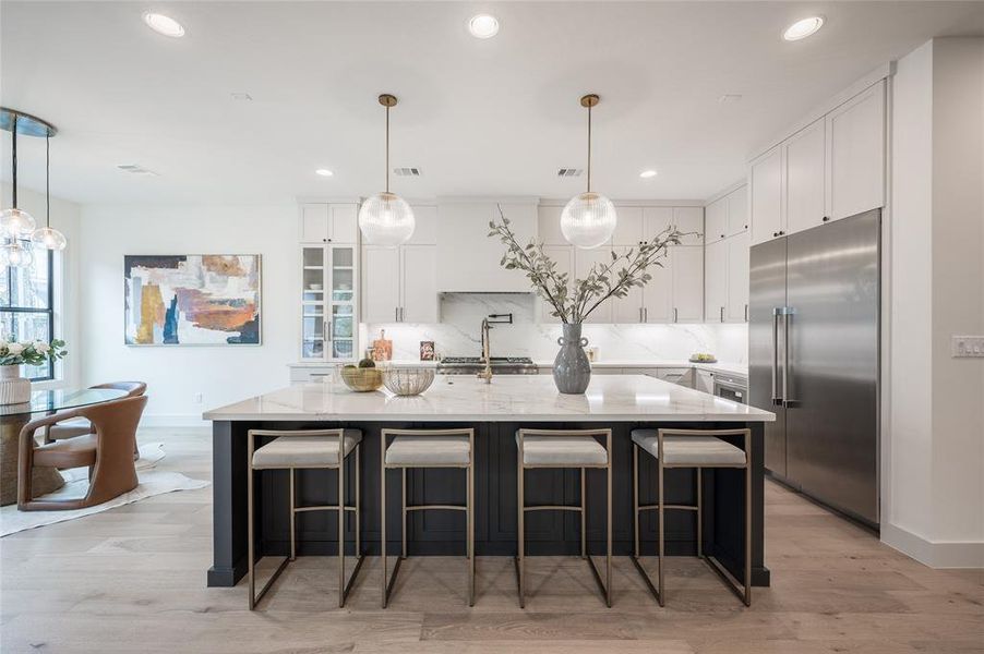 The open gourmet kitchen elevates every culinary endeavor with sleekcustom cabinetry trimmed with undercabinet lighting and gorgeous Calacatta marblecountertops.