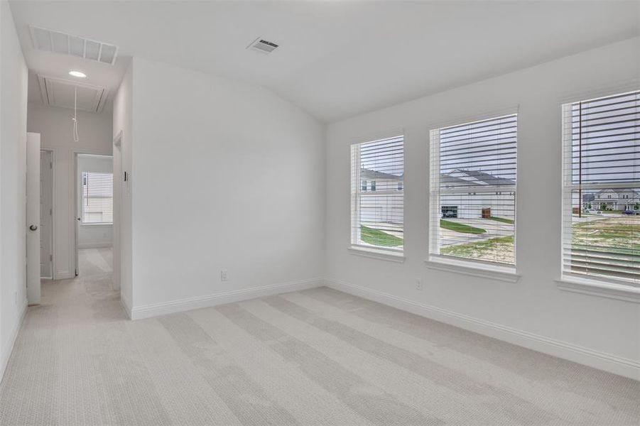 Carpeted empty room featuring vaulted ceiling