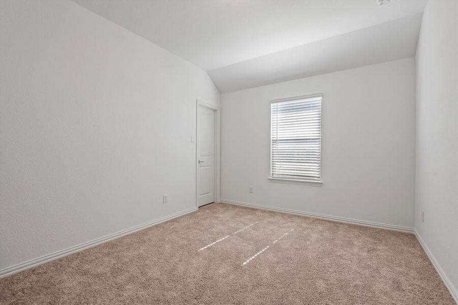 Carpeted spare room with vaulted ceiling