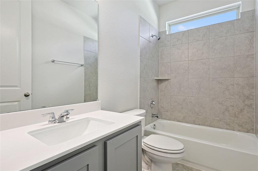 Full bathroom with tiled shower / bath, vanity, and toilet