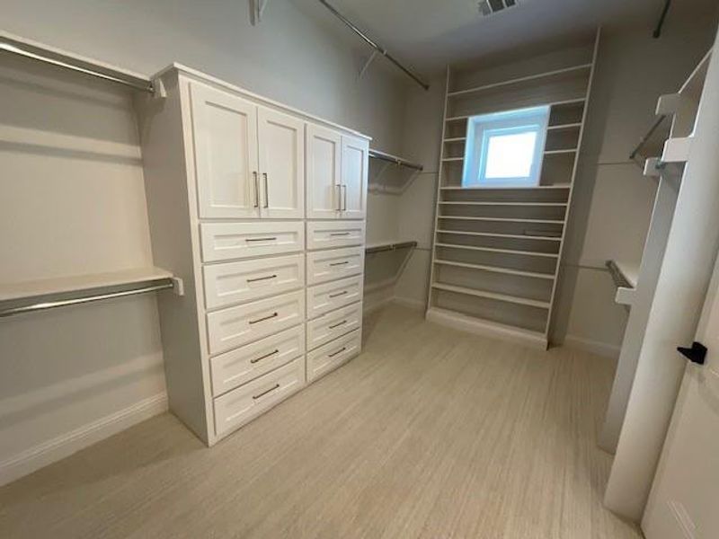 Walk in closet with light hardwood / wood-style flooring