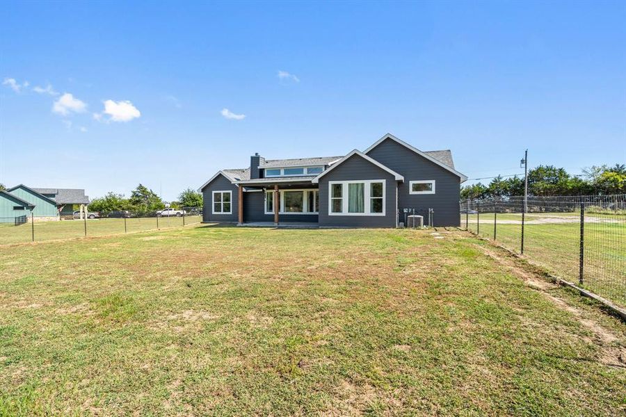 Rear view of property with a patio area, central air condition unit, and a yard