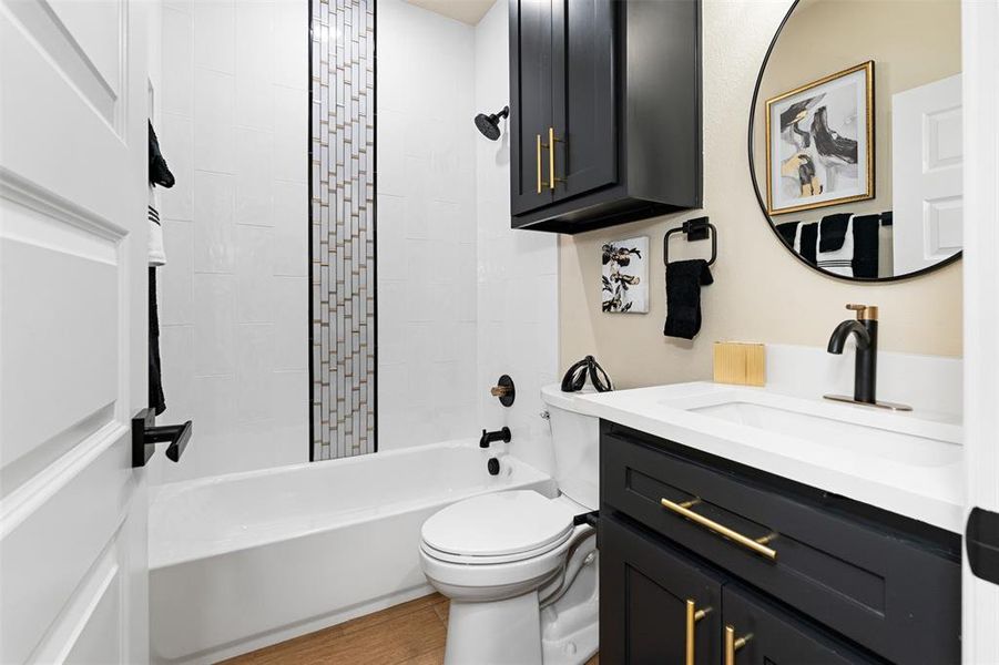 Full bathroom with toilet, vanity, tiled shower / bath, and hardwood / wood-style flooring