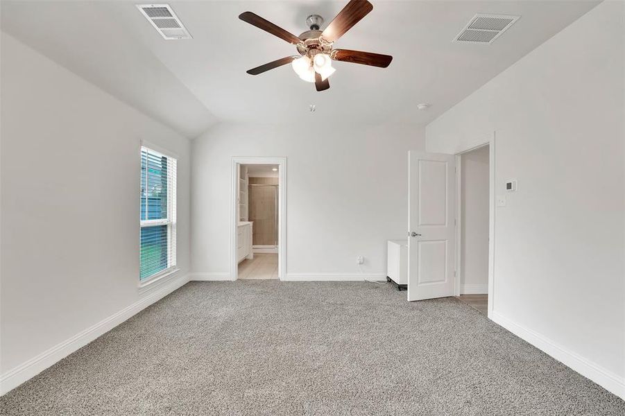 Unfurnished bedroom featuring ceiling fan, connected bathroom, light carpet, and lofted ceiling