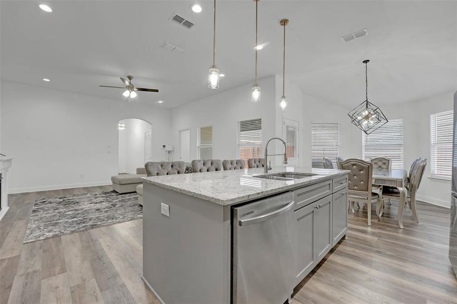 Kitchen featuring stainless steel dishwasher, a wealth of natural light, a center island with sink, and sink