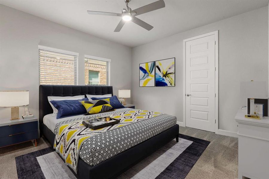 Secondary bedroom great for use as an in-law suite or guest suite features high ceilings, modern ceiling fan, neutral paint, plush carpet, space for seating area, direct access to the secondary bathroom and large windows with privacy blinds.