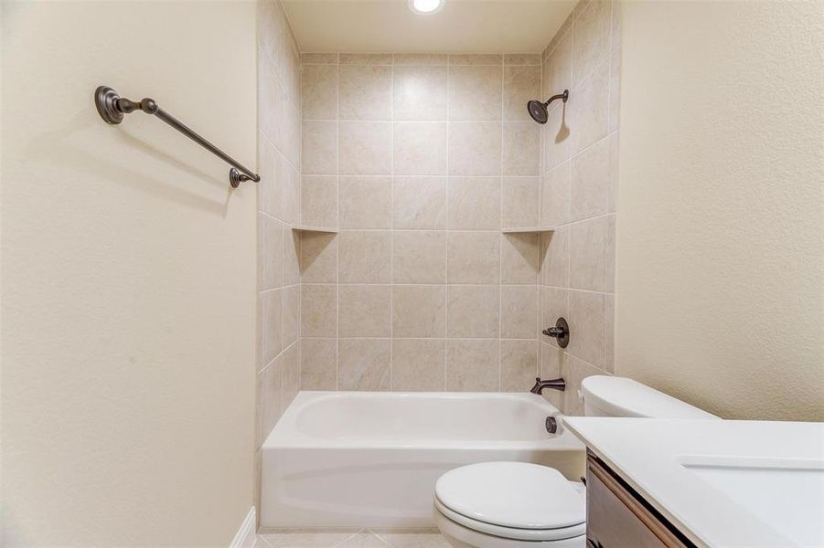 Full bathroom featuring tiled shower / bath combo, tile patterned floors, toilet, and vanity