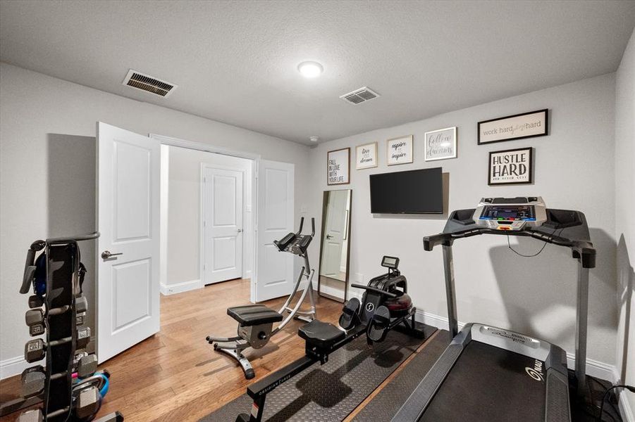 Workout room with a textured ceiling and light hardwood / wood-style flooring