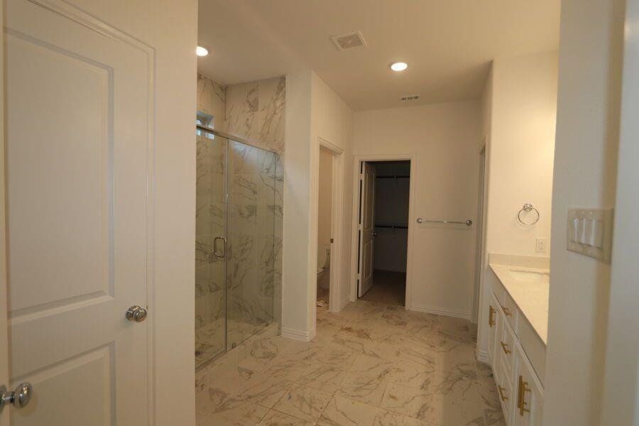 Bathroom featuring walk in shower, vanity, and toilet