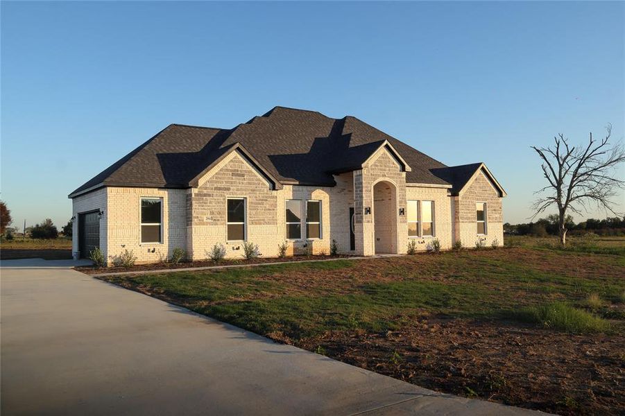 French country inspired facade featuring a front yard and a garage