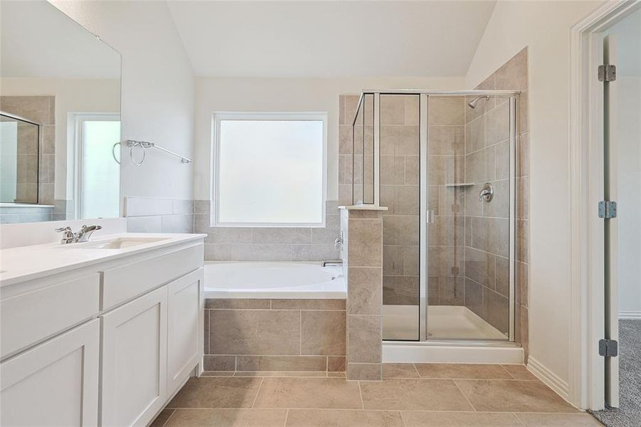 Bathroom with vanity, vaulted ceiling, plus walk in shower, and tile patterned floors