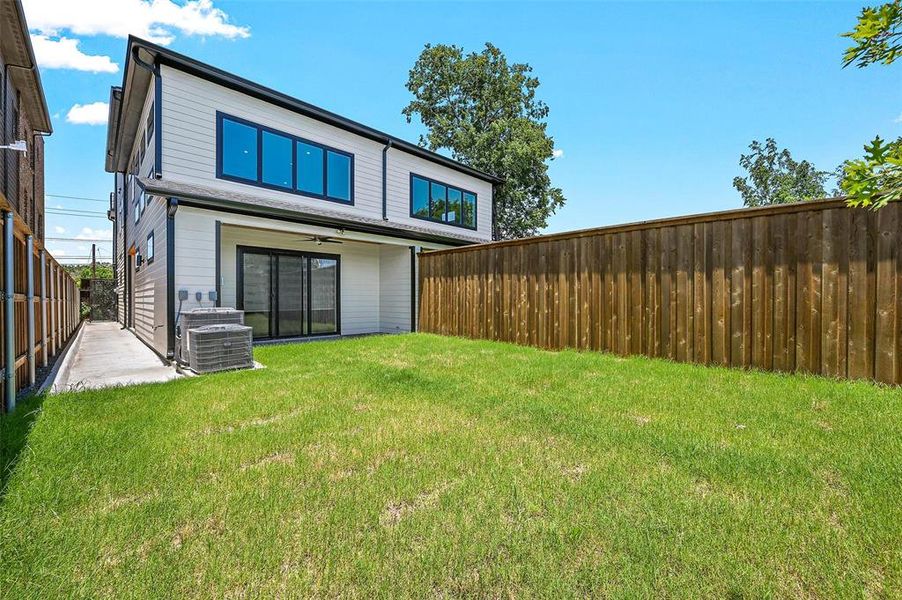 Rear view of property with cooling unit and a lawn