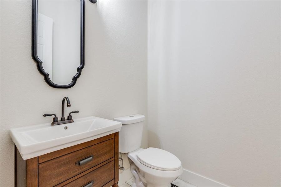 Half Bathroom featuring vanity, tile patterned flooring, and toilet