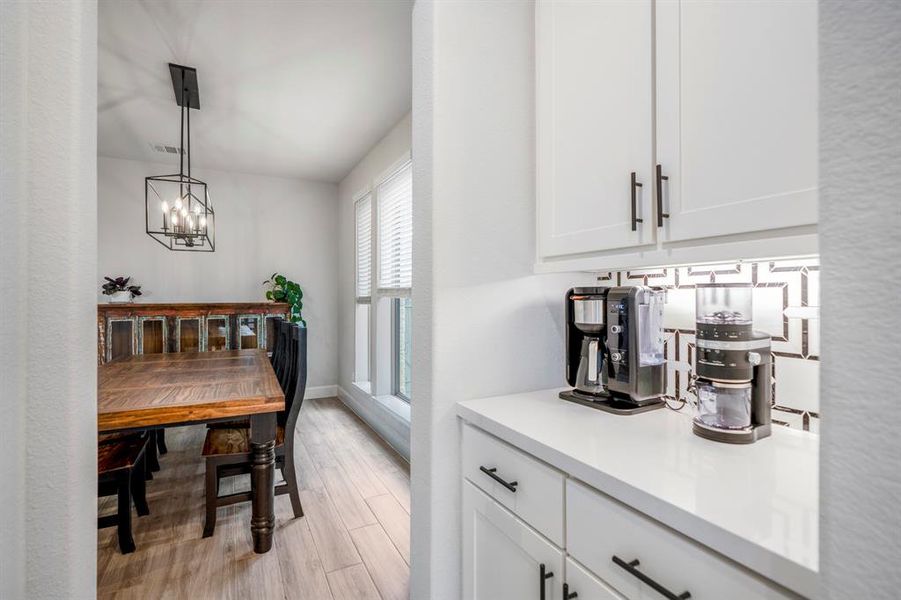 The butler's pantry connects the dining and kitchen making it a wonderful space to entertain guests! It's the perfect area for a coffee or wine bar with quartz counters, under cabinet lighting, and a modern backsplash.