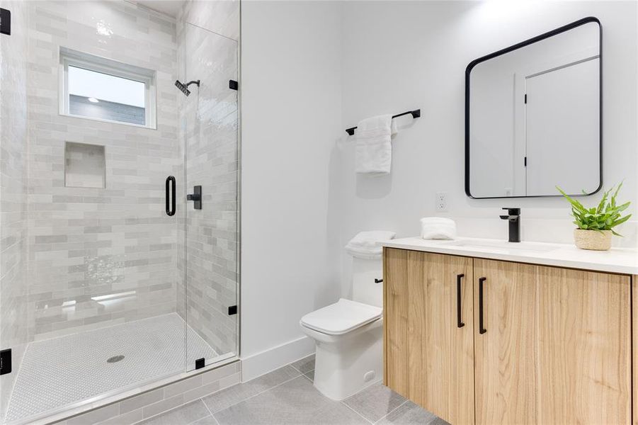 Bathroom with an enclosed shower, tile patterned floors, vanity, and toilet