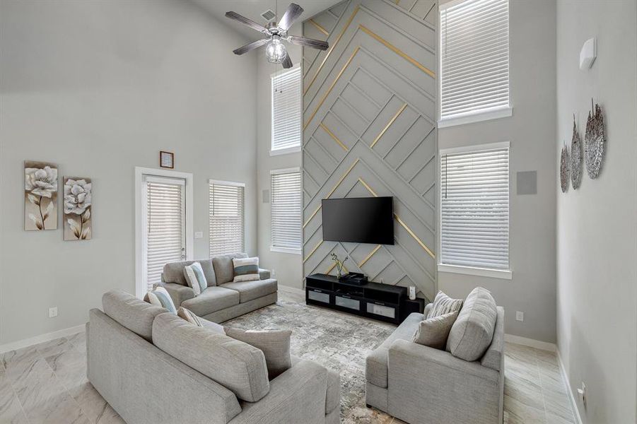 Living room featuring a towering ceiling, a wealth of natural light, and ceiling fan