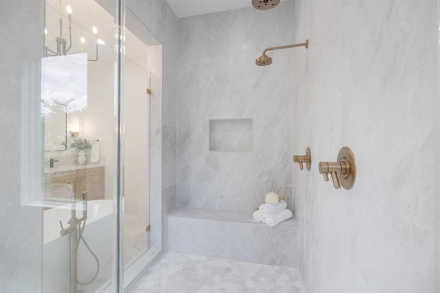 Shower features dual shower heads, bench and large format modern tiles.