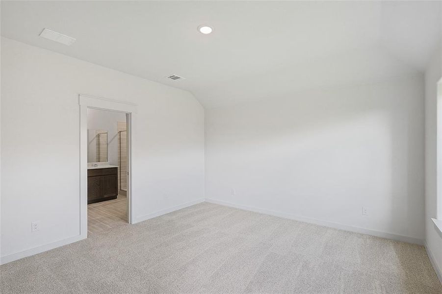 Carpeted spare room with vaulted ceiling