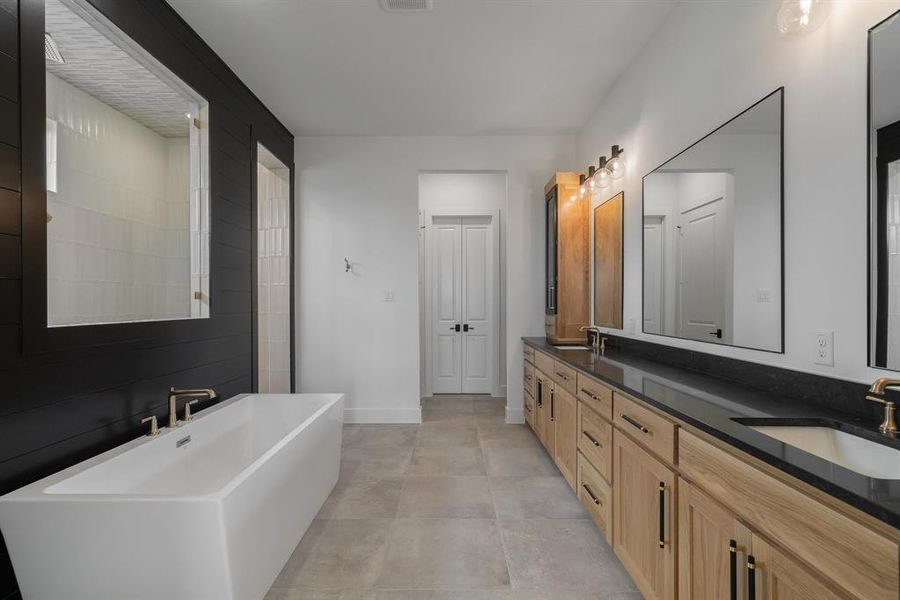 Bathroom featuring a tub, tile patterned floors, and double sink vanity