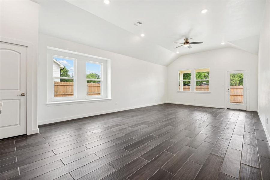 Unfurnished living room featuring vaulted ceiling, plenty of natural light, ceiling fan, and dark hardwood / wood-style floors