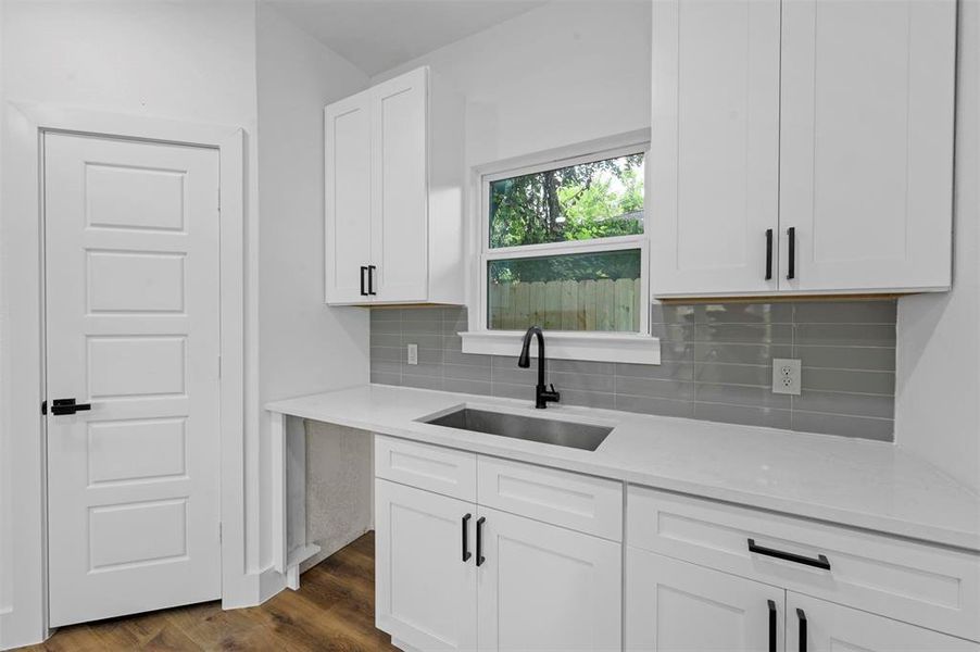Kitchen with white cabinetry, dark hardwood / wood-style flooring, decorative backsplash, sink, and light stone counters