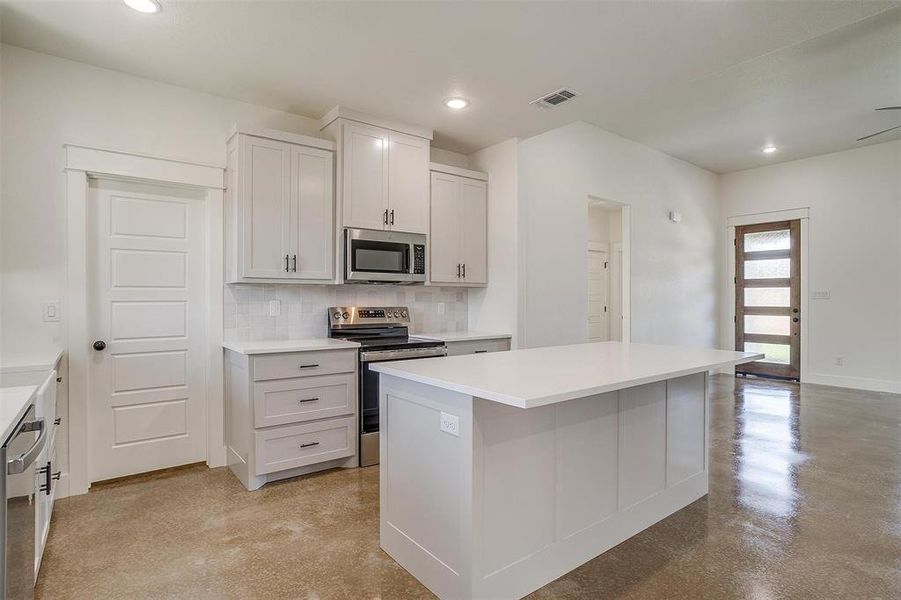 Kitchen featuring backsplash, appliances with stainless steel finishes, a center island, and white cabinets