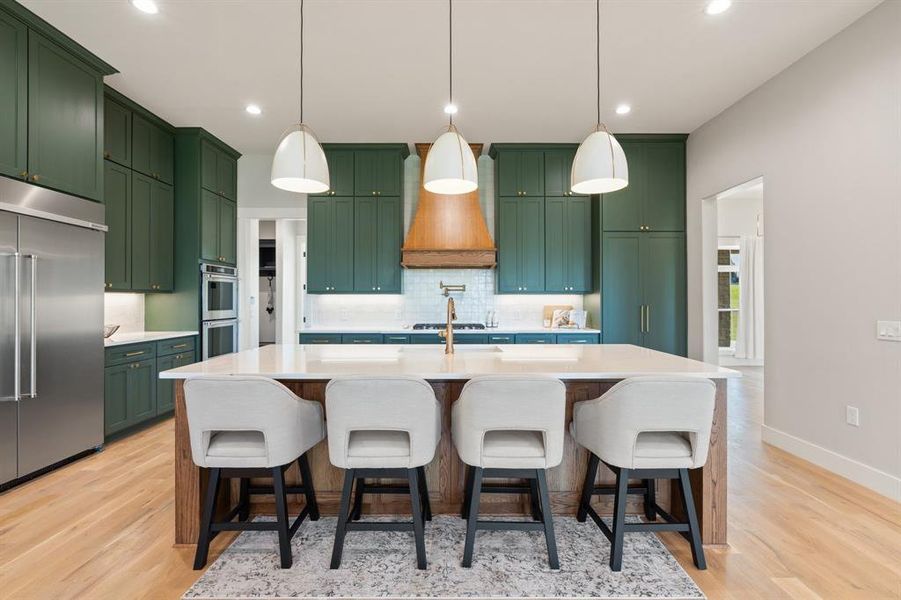 Kitchen featuring decorative light fixtures, light hardwood / wood-style flooring, and stainless steel appliances