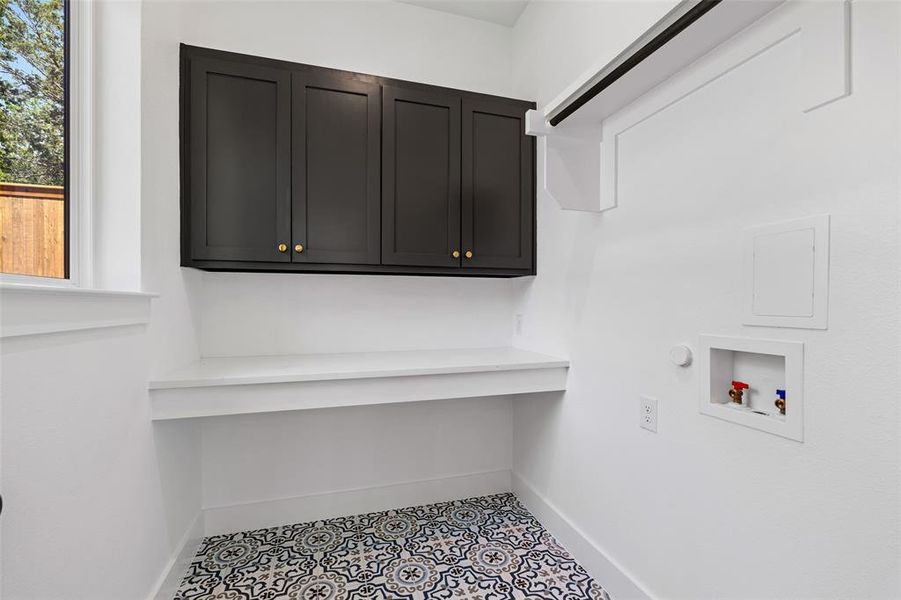 Laundry room with hookup for a washing machine, light tile patterned floors, and cabinets