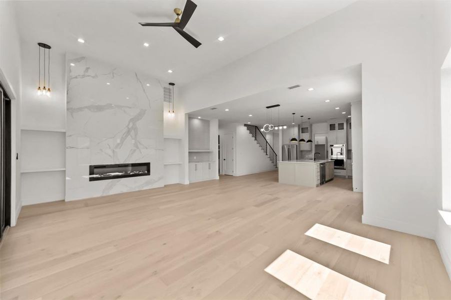 Living room featuring light wood-type flooring, a premium fireplace, and ceiling fan