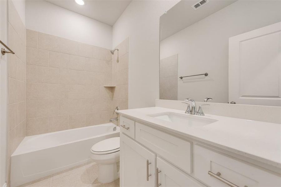 Full bathroom featuring vanity, toilet, tile patterned floors, and tiled shower / bath