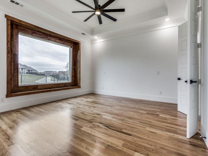 Unfurnished room featuring hardwood / wood-style floors, ceiling fan, a tray ceiling, and crown molding
