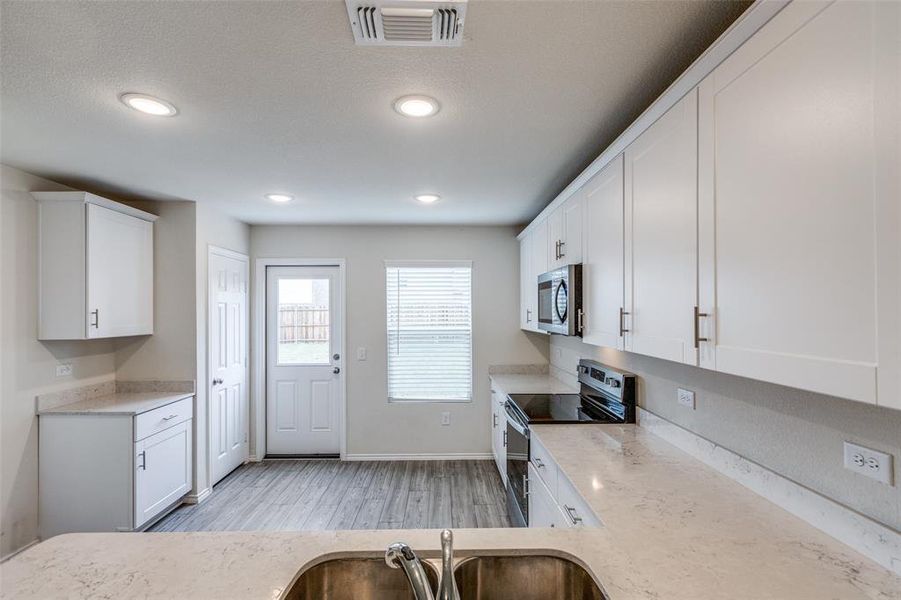 Kitchen featuring stainless steel appliances, white cabinetry, sink, and light wood-type flooring