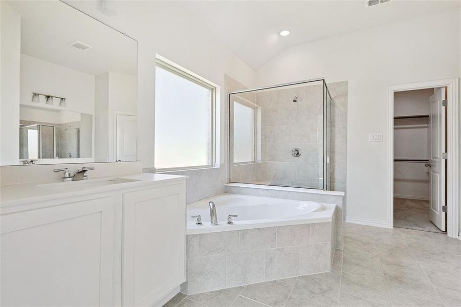 Bathroom featuring tile patterned floors, shower with separate bathtub, lofted ceiling, and vanity