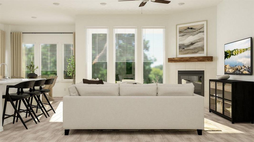 Living room featuring a tile fireplace, ceiling fan, light wood-type flooring, and plenty of natural light