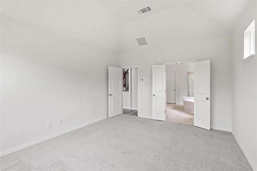 Unfurnished bedroom with vaulted ceiling and light carpet