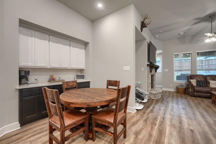 Dining area with a fireplace, ceiling fan, and light hardwood / wood-style flooring