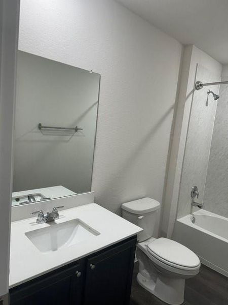 Full bathroom with shower / washtub combination, vanity, toilet, and hardwood / wood-style flooring