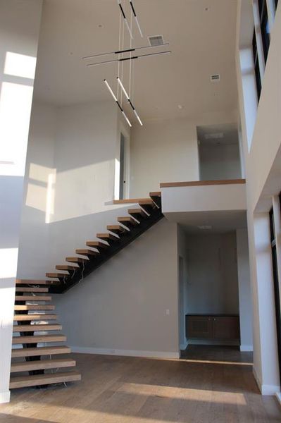 Staircase with an inviting chandelier, a towering ceiling, and hardwood / wood-style floors