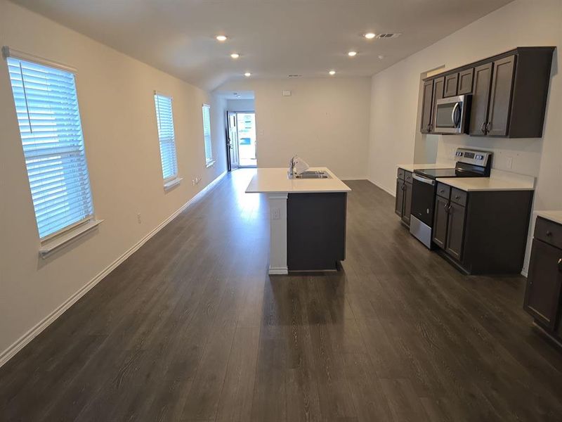 Kitchen with an island with sink, stainless steel appliances, dark wood-type flooring, and sink