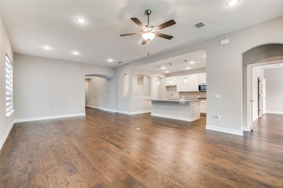 Unfurnished living room with dark wood-type flooring, ceiling fan, and sink