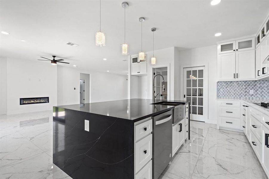 Kitchen featuring ceiling fan, dishwasher, an island with sink, and white cabinetry