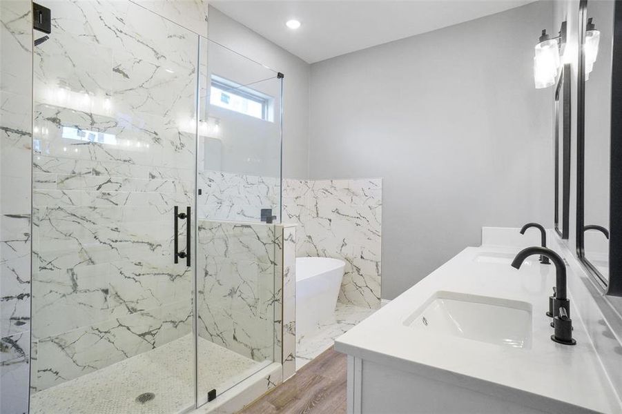 Bathroom with tile walls, hardwood / wood-style floors, an enclosed shower, and dual bowl vanity