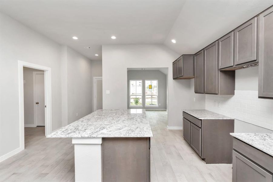 This generously spacious layout boasts a massive granite island, high ceilings, soft-close cabinets, granite countertops, stainless steel appliances (to be installed), a sleek tile backsplash, and recessed lighting. Sample photo of completed home with similar floor plan. As-built interior colors and selections may vary.
